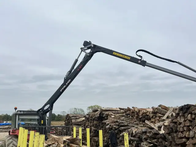 Grue de tracteur au-dessus de piles de bois